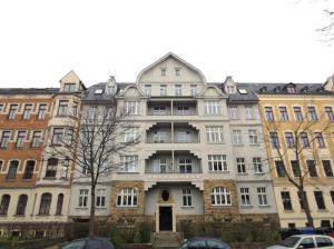 開姆尼茨的住宿－Stylisches City Appartment in Chemnitz bester Lage!，一座白色的大建筑,前面有汽车停放