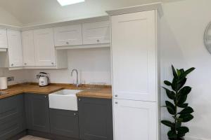 a kitchen with white cabinets and a sink at Boundary Stable in Pickering