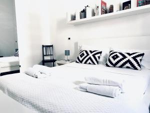 una camera da letto con un letto bianco con cuscini bianchi e neri di U Palazzieddu Rooms a Pachino