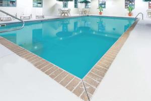 a swimming pool with blue water and a tile floor at Wingate by Wyndham Airport - Rockville Road in Indianapolis