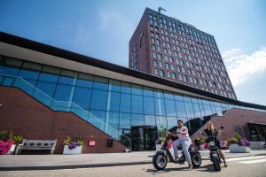 dos personas en motocicleta frente a un edificio en Van der Valk Hotel Hoorn, en Hoorn