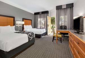 um quarto de hotel com duas camas e uma secretária e uma televisão em La Quinta by Wyndham Dallas - Addison Galleria em Addison