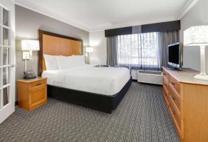 a hotel room with a bed and a flat screen tv at La Quinta by Wyndham Dallas - Addison Galleria in Addison