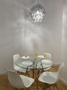 comedor con mesa de cristal y sillas blancas en Aluche Aparment B, en Madrid