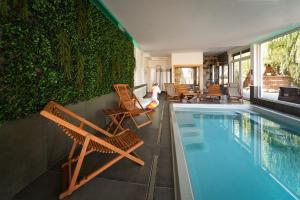 a swimming pool with chairs and a green wall at Grand House 47 in Boguszyn
