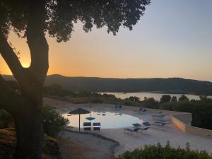 a pool with chairs and umbrellas next to a lake at Hotel Valkarana Country Relais in Sant Antonio Di Gallura