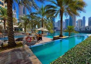 una piscina con palme e una città di Nasma Luxury Stays - Pastel-Colored Apt With Jaw-Dropping Marina Views a Dubai