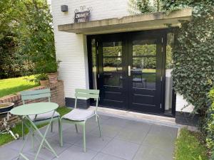 een patio met een tafel en stoelen en een zwarte deur bij La Grange 28 in Bergen op Zoom