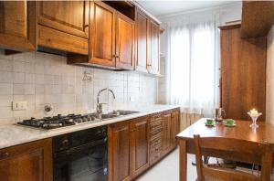 cocina con armarios de madera, fregadero y mesa en SILVIA'S HOME en Venecia