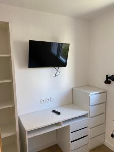 a white desk with a flat screen tv on a wall at Les lodges du chateau in Marquise