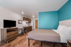 a bedroom with a bed and a tv and a desk at WoodSpring Suites | North Charleston Airport I-526 in Charleston