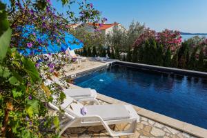 a swimming pool with two lounge chairs and flowers at Luton Apartment Zadar Kozino Heating Pool & Jacuzzi in Kožino