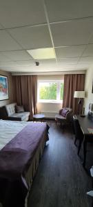 um quarto de hotel com uma cama grande e uma secretária em First Hotel Royal em Säffle