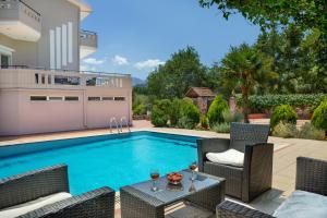a swimming pool with chairs and a table next to a house at Villa Marianna in Vryses