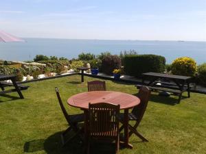 uma mesa de madeira e cadeiras num relvado com o oceano em The Cliff Hall em Shanklin