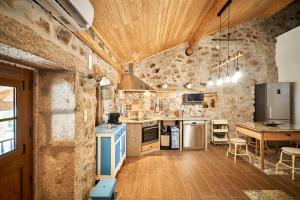a kitchen with stone walls and a wooden ceiling at Casa Fonte da Mina in Fundão