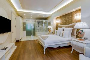 a bedroom with a large white bed and a television at Polat Thermal Hotel in Pamukkale