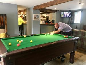 a man playing pool in a room with a pool table at Kings Head - Riverside, Ravenstonedale in Ravenstonedale