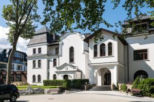 a white house with a tree in front of it at Nosalowy Park Hotel & Spa in Zakopane