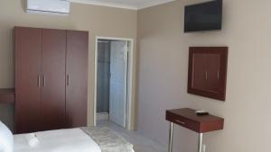 Un dormitorio con una cama y un televisor en la pared. en Villa Strada Guesthouse, en Klerksdorp 20 fotos más