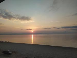 a sunset on the beach with the sun setting over the water at House Kohili in Nea Vrasna