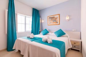um quarto com 2 camas e cortinas azuis em Hostal Ferrer em San Antonio