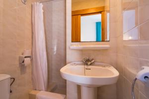 ein Badezimmer mit einem Waschbecken, einem Spiegel und einem WC in der Unterkunft Hostal Ferrer in Sant Antoni de Portmany