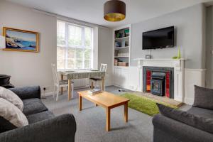 a living room with a couch and a table and a fireplace at The Courtyard Cirencester in Cirencester