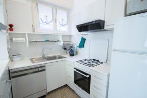 una pequeña cocina blanca con fregadero y fogones en Grande BILOCALE con GIARDINO e POSTO AUTO PRIVATO Comodo al mare en Varazze