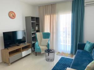 a living room with a tv and a couch and a chair at Tatli Apartment in Famagusta