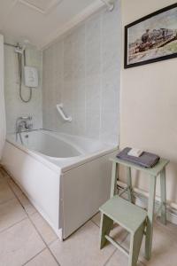 a white bath tub in a bathroom with a stool at The Courtyard Cirencester in Cirencester