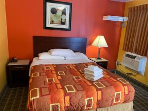 sypialnia z dużym łóżkiem z pomarańczową ścianą w obiekcie Scottish Inns Wrightstown w mieście Wrightstown