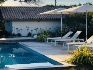 - une piscine avec 2 chaises et un parasol dans l'établissement Le Cabanon Bidart, à Bidart