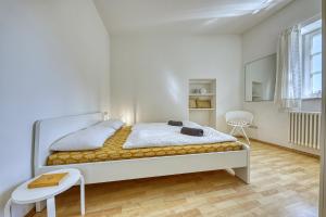 een witte slaapkamer met een bed en een stoel bij Zentral gelegenes Apartment mit Garage & kleinem Außenbereich in Caldaro