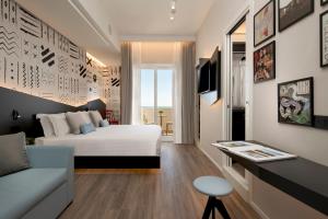 1 dormitorio con cama, escritorio y sofá en Litoraneo Suite Hotel, en Rímini