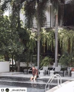 a man sitting in a pool next to a building at Manita Boutique Hotel in Pattaya South