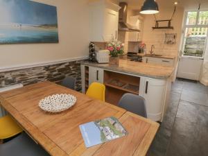 a kitchen with a wooden table and yellow chairs at Fairfield Cottage in Boscastle