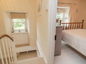 a bedroom with a bed and a window and a staircase at Fairfield Cottage in Boscastle