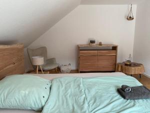 a bedroom with a bed with a dresser and a chair at Familie Mettler in Haltingen