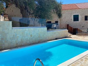 a swimming pool in front of a house with a stone wall at Kuća za odmor "Villa Oliva" in Ivan Dolac
