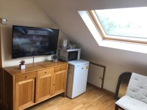 sala de estar con TV y nevera pequeña en S6 Ensuite Loft Studio Space (Sandycroft Guest House), en Londres