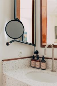 a bathroom sink with a mirror and two bottles of soap at Hôtel Wallace - Orso Hotels in Paris