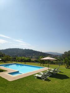 a swimming pool with lawn chairs and an umbrella at Casa do Pomarelho in Póvoa de Lanhoso