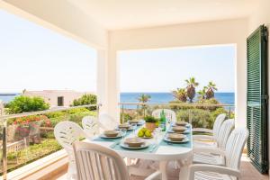 a white table and chairs on a balcony with the ocean at Villa Juaneda in Ciutadella