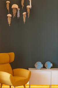 sala de estar con silla amarilla y pared en Sea La Vie house, close to the beach, By ThinkVilla, en Panormos Rethymno
