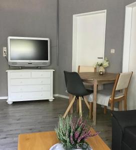 sala de estar con TV y mesa de comedor en Apartment am Park -Calluna en Schneverdingen