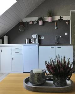 a kitchen with white cabinets and a table with plants at Apartment am Park -Calluna in Schneverdingen