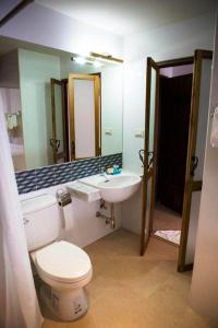 een badkamer met een toilet, een wastafel en een spiegel bij Hotel Toscana Trat in Trat