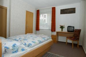 a bedroom with a bed and a desk and a television at Hotel Terminus in Mainz