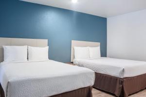 2 łóżka w pokoju z niebieskimi ścianami w obiekcie WoodSpring Suites Amarillo East I-40 w mieście Amarillo